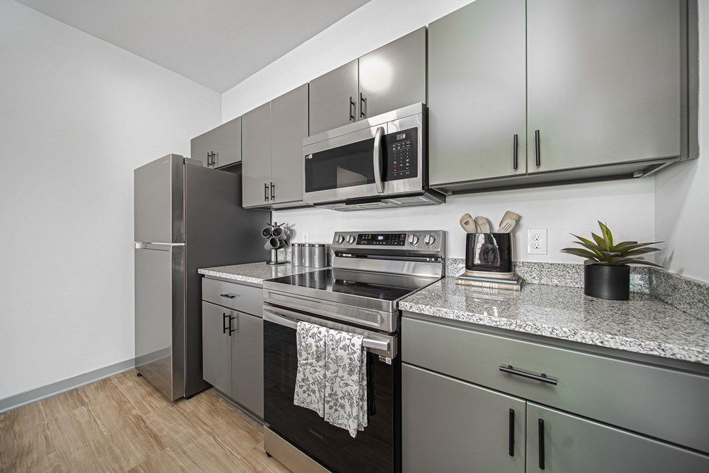 A modern kitchen with stainless steel appliances and a wooden floor.