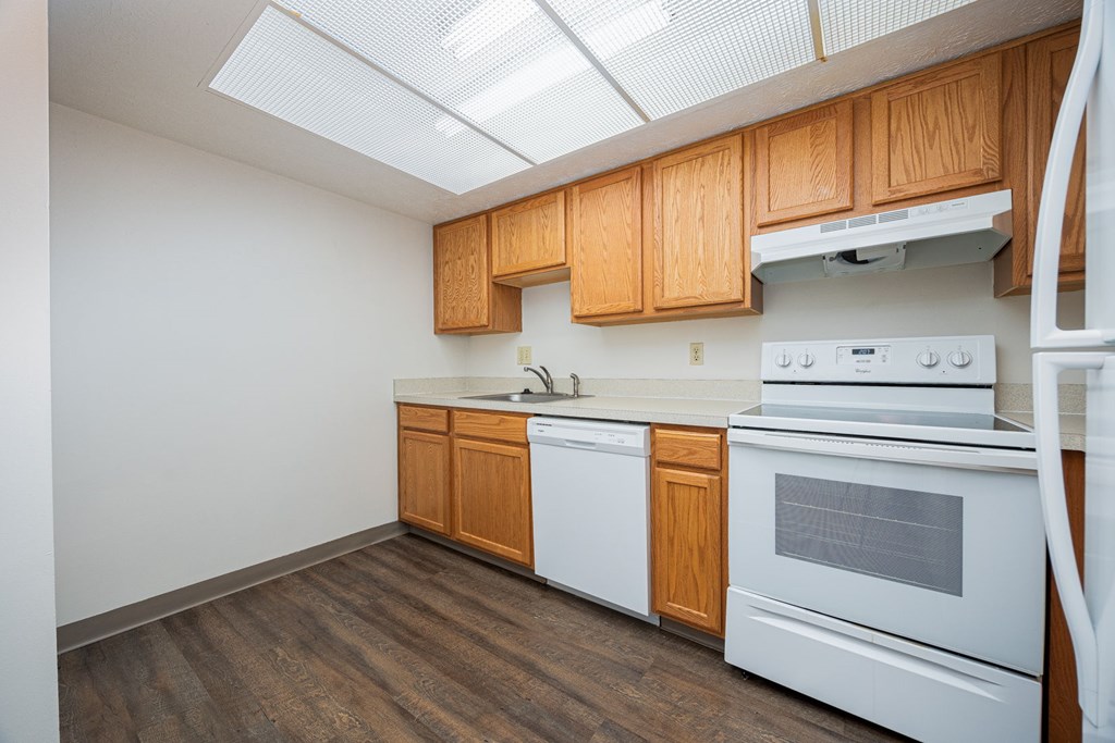 A kitchen with white appliances and wooden cabinets.
