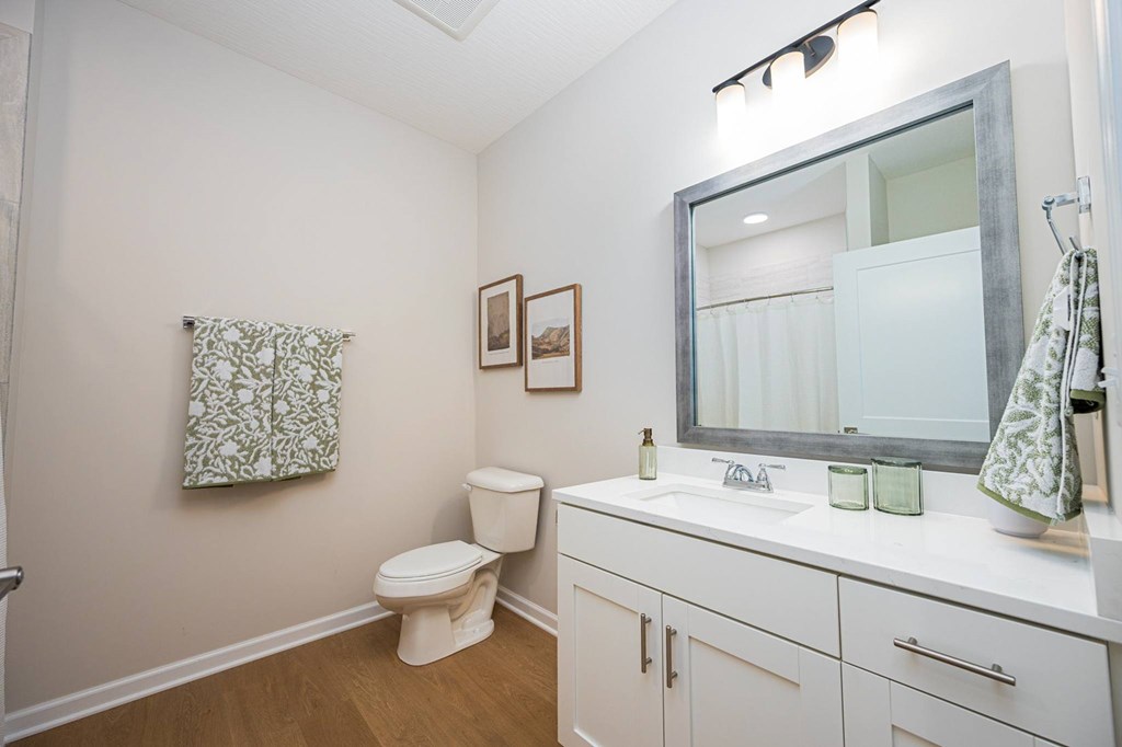 A white bathroom with a toilet, sink, and mirror.