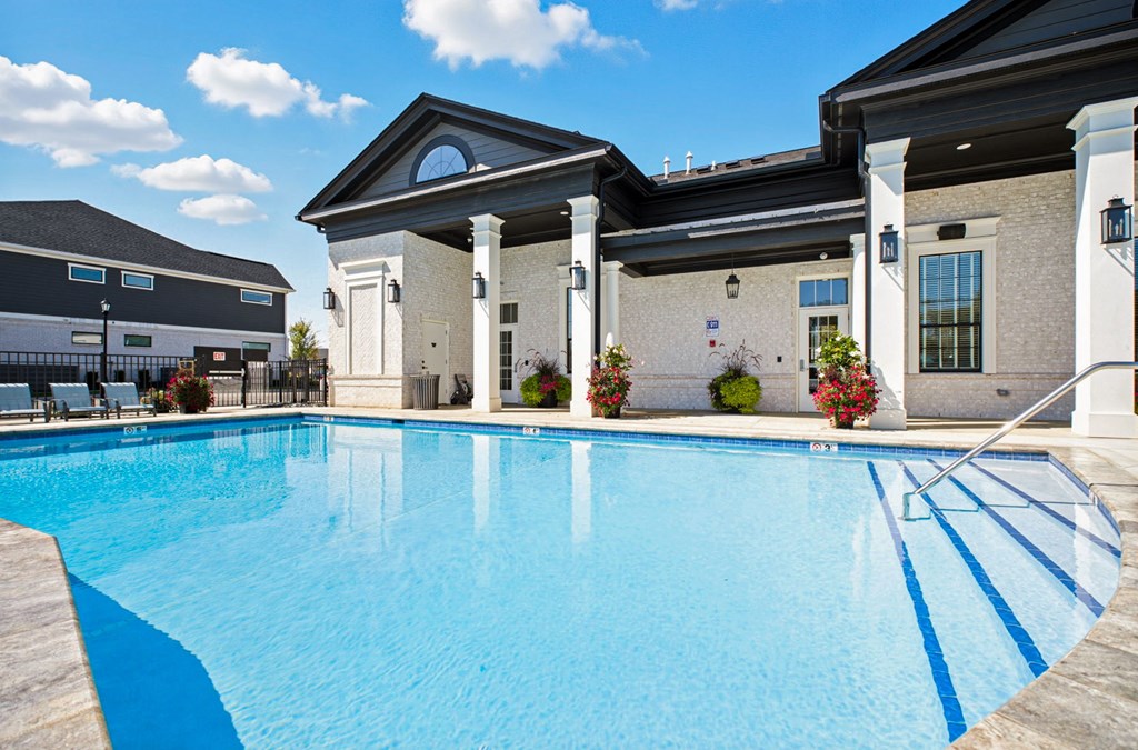 A large swimming pool in front of a building with a white pillar.