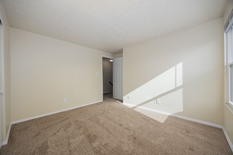 A room with a carpeted floor and a door in the background.