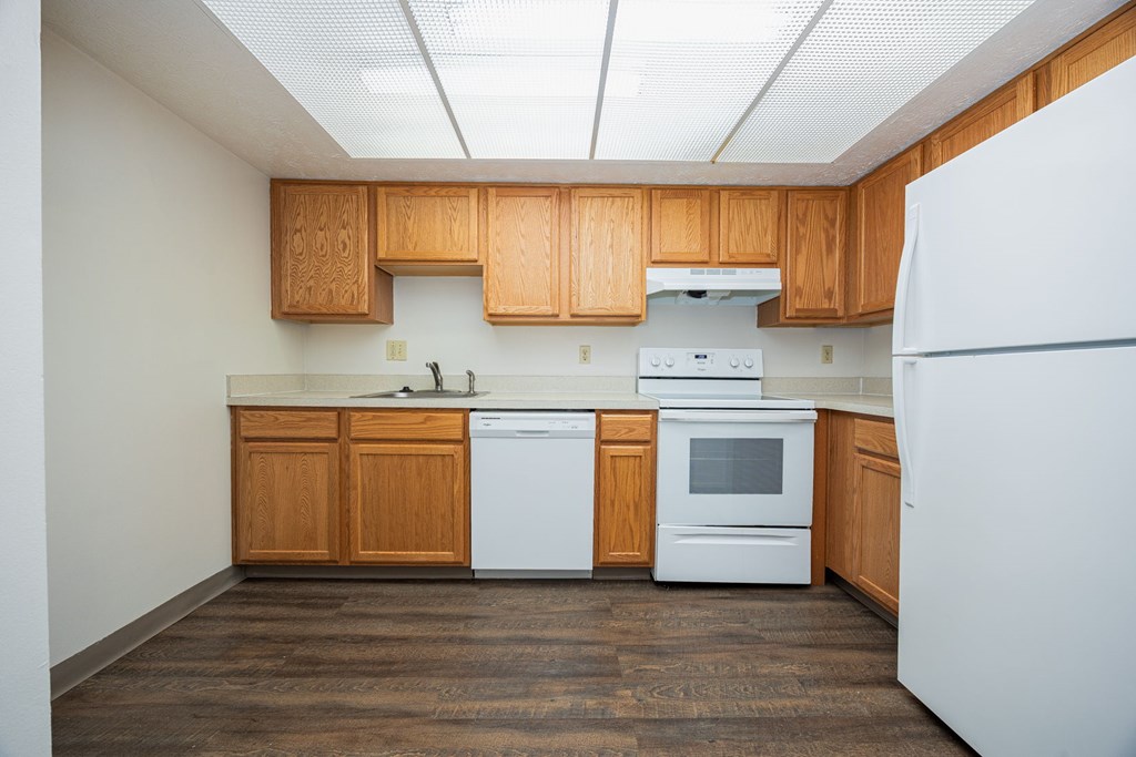 A kitchen with white appliances and wooden cabinets.