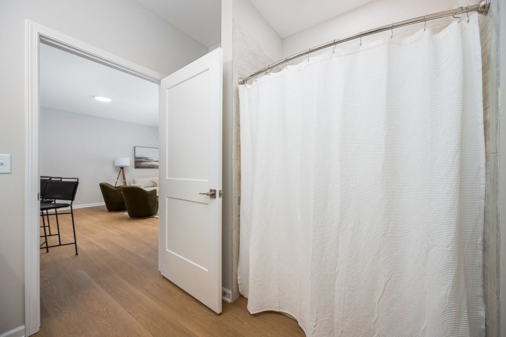 A white door is open to a room with a chair and a plant.