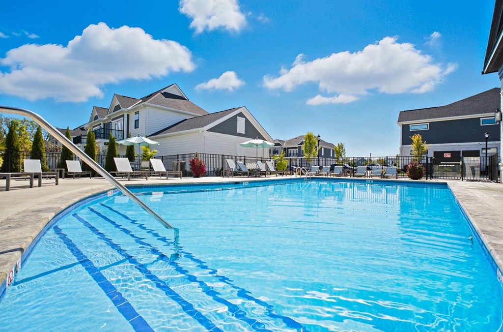 A large blue swimming pool with a diving board in the foreground.