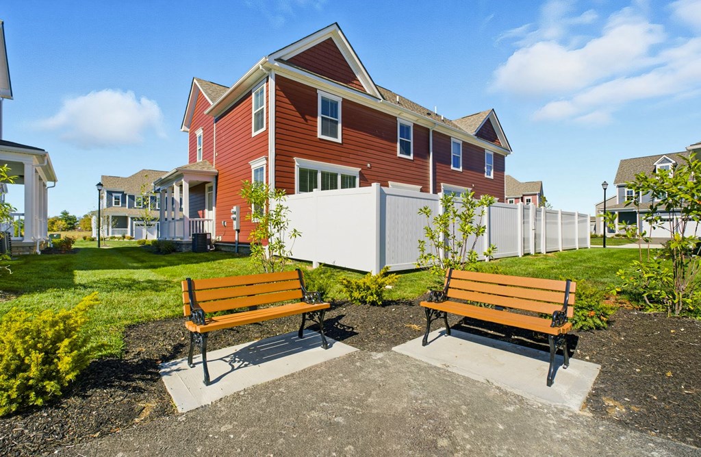 Two wooden benches are placed in front of a red building.