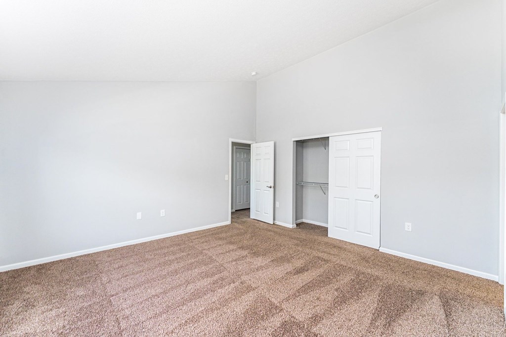 A room with carpeted floor and two white doors.