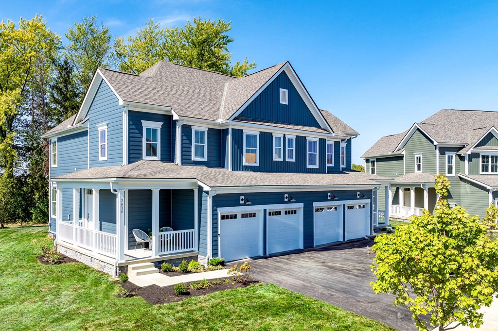 A blue house with a white porch and a garage.