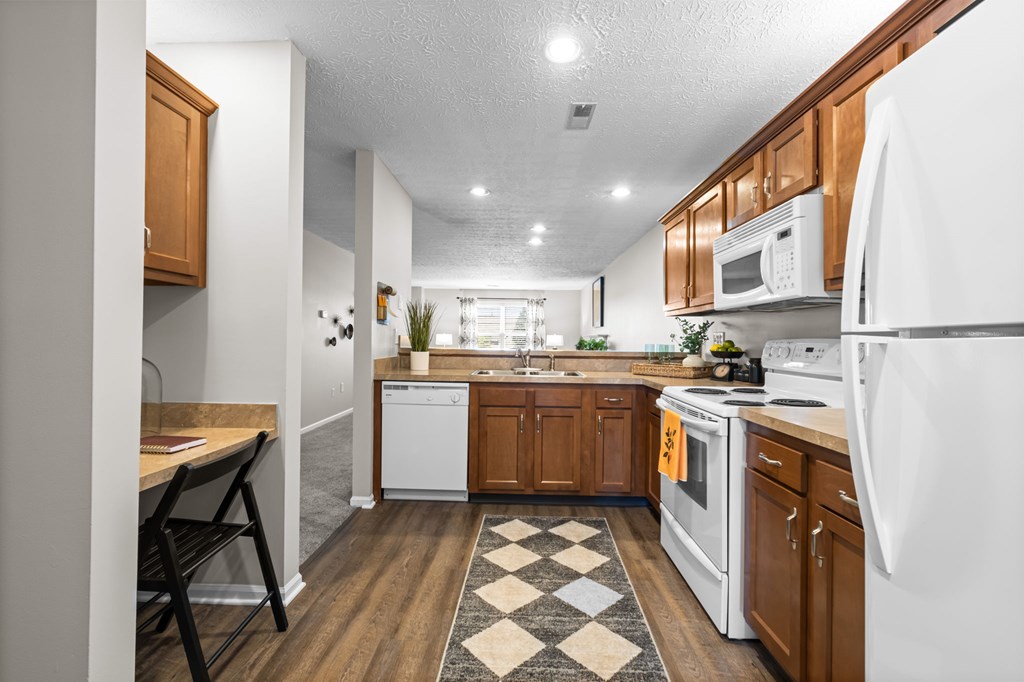 A kitchen with white appliances and wooden cabinets.