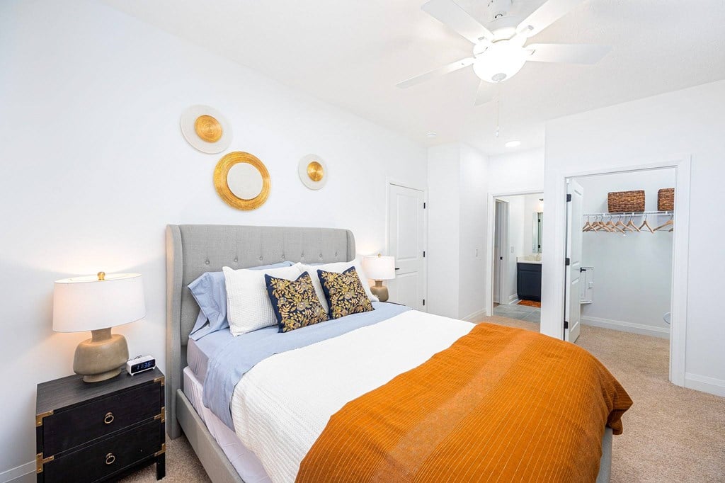 A bedroom with a bed, nightstand, and a ceiling fan.