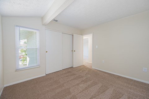 a spacious living room with carpet and a door to a bedroom