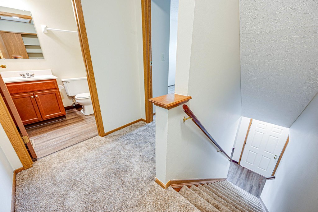 the landing of a staircase in a home with a bathroom and a toilet