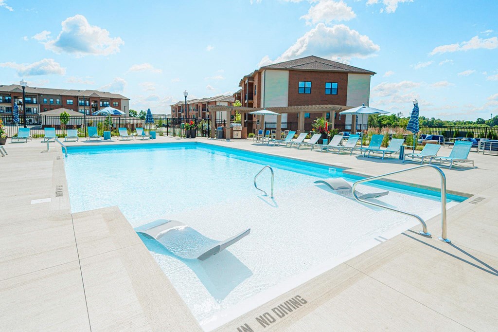 a swimming pool with chairs and a building in the background