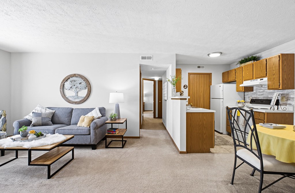 A living room with a grey couch, a coffee table, and a dining area with a yellow tablecloth.