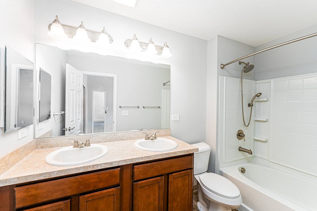 A white bathroom with a double sink and a toilet.