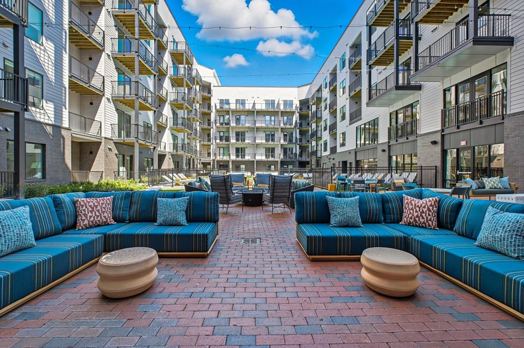 A courtyard with a blue couch and a brick floor.