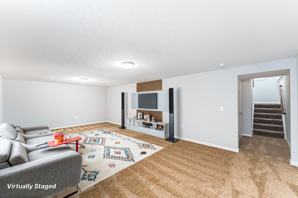 A living room with a grey couch and a rug with a pattern on it.