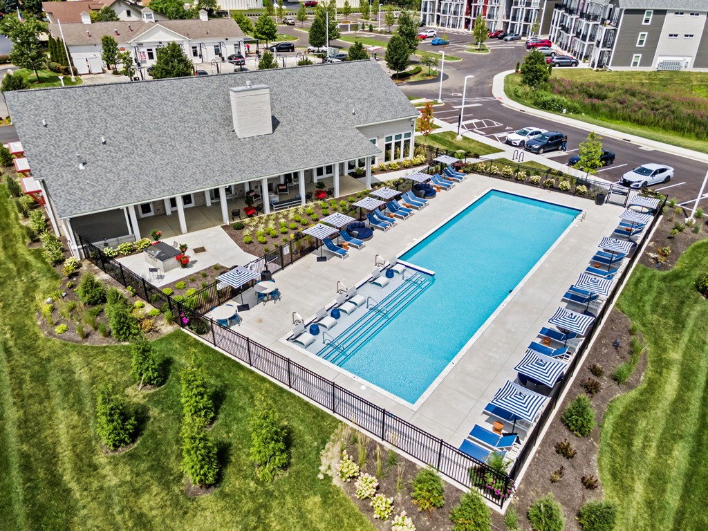 An aerial view of a pool surrounded by chairs and a building in the background.