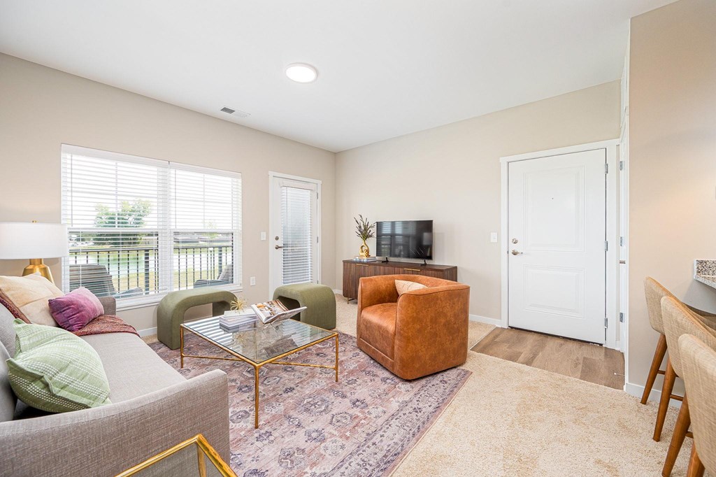 A living room with a grey couch, a brown chair, a glass coffee table, and a television.