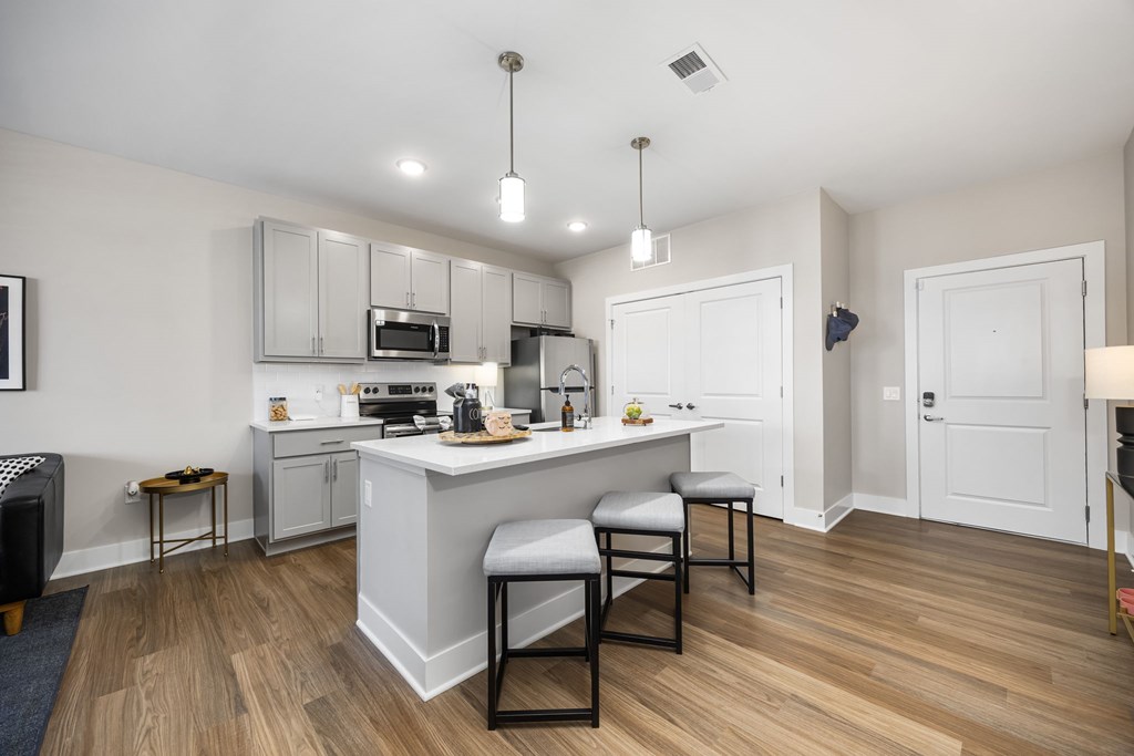 A kitchen with a white island and black chairs.
