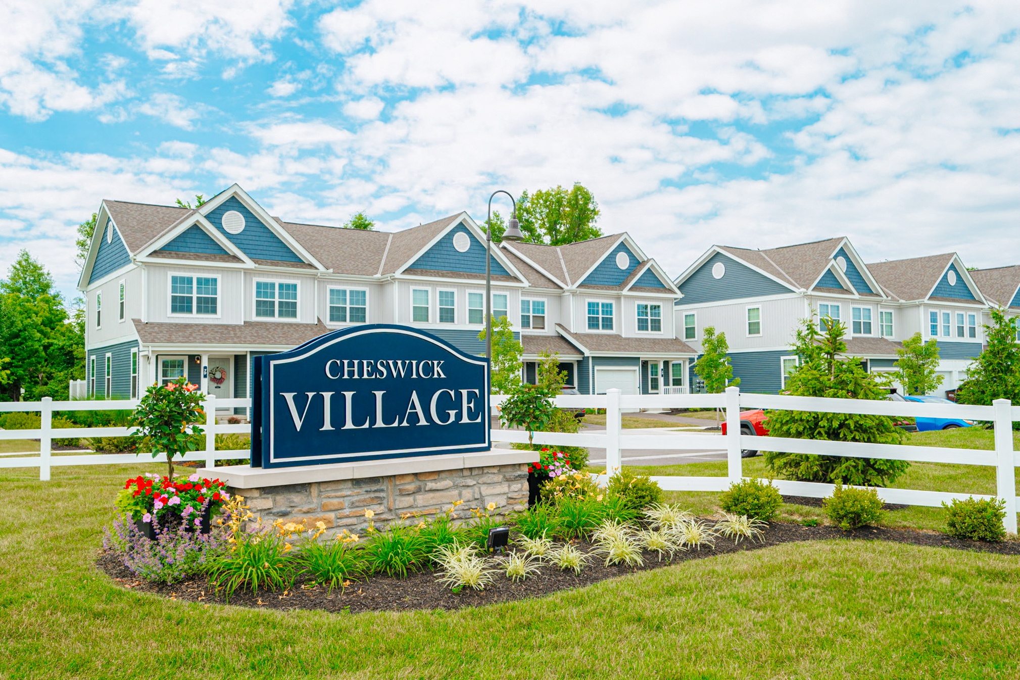 the village apartments sign in front of fence and building