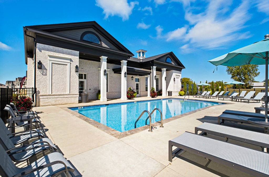 A pool area with sun loungers and a building in the background.