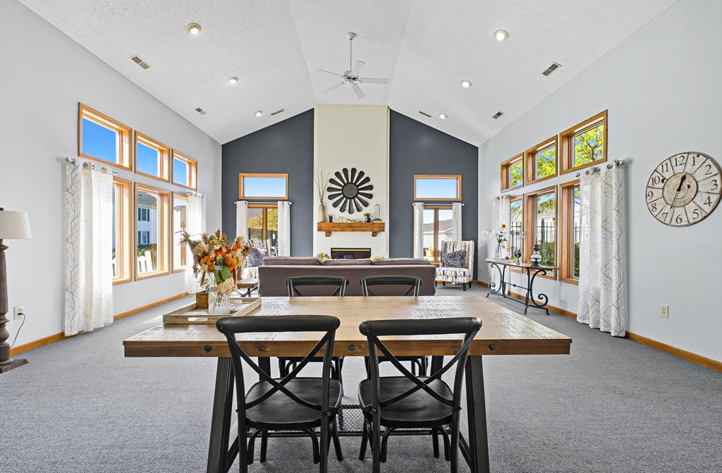 A dining room with a table set for two and a clock on the wall.