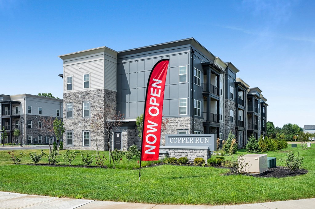 A sign in front of a building that says "Now Open".