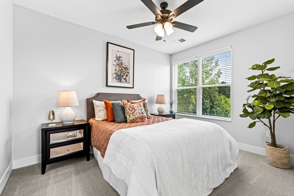 A bedroom with a bed, nightstand, and a ceiling fan.