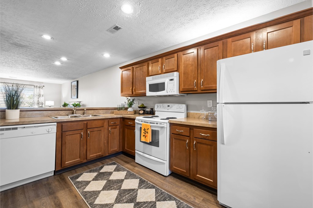 A kitchen with white appliances and wooden cabinets.