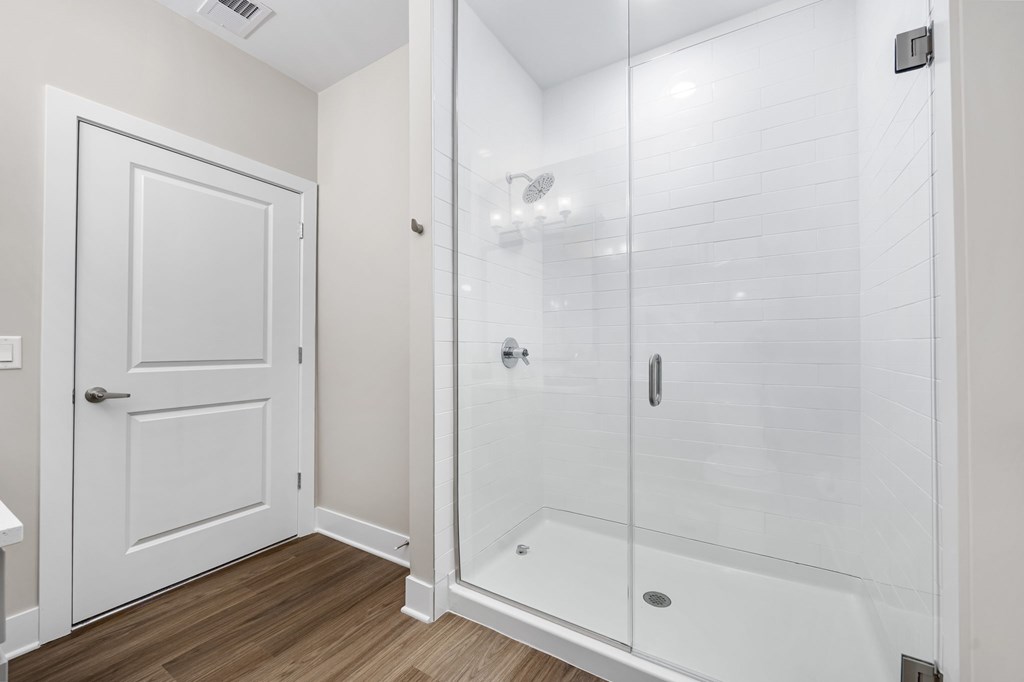 A white bathroom with a walk-in shower and a door.