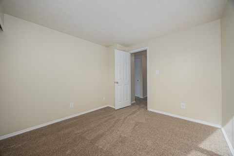 A room with a carpeted floor and a white door.