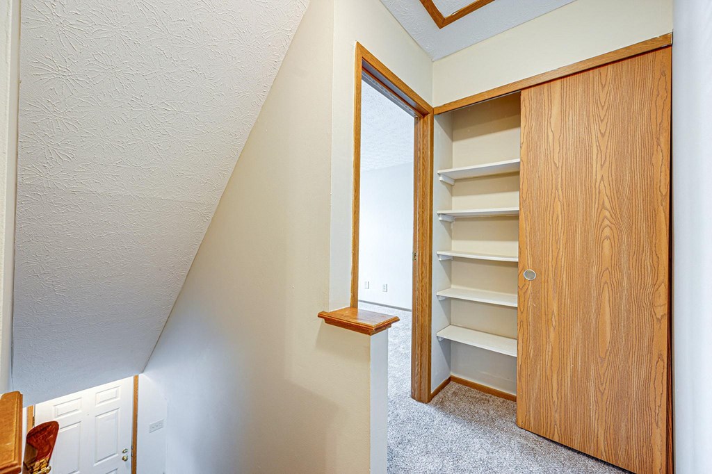 a closet in a upstairs room with a window and a door