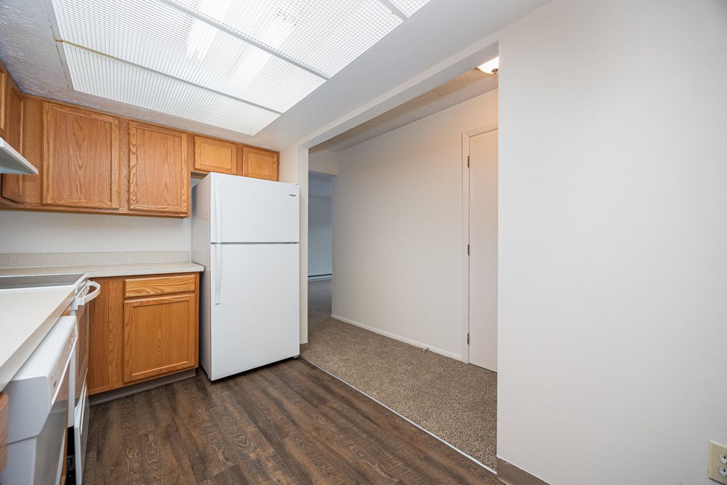 A kitchen with a white refrigerator and wooden cabinets.