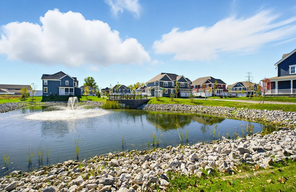 A pond with a fountain in the middle of a residential area.