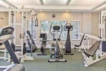 a gym with cardio equipment and weights on the floor