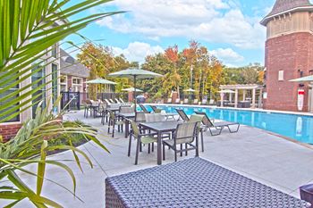 a swimming pool with tables and chairs next to a pool