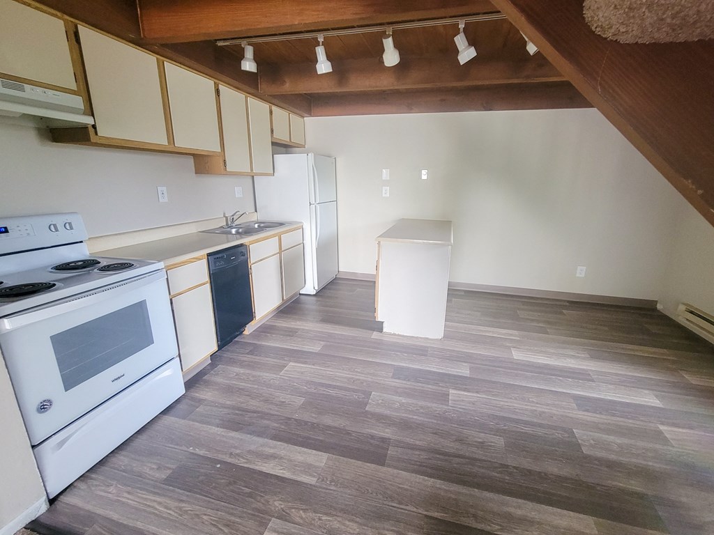 a kitchen with white appliances and a wooden floor