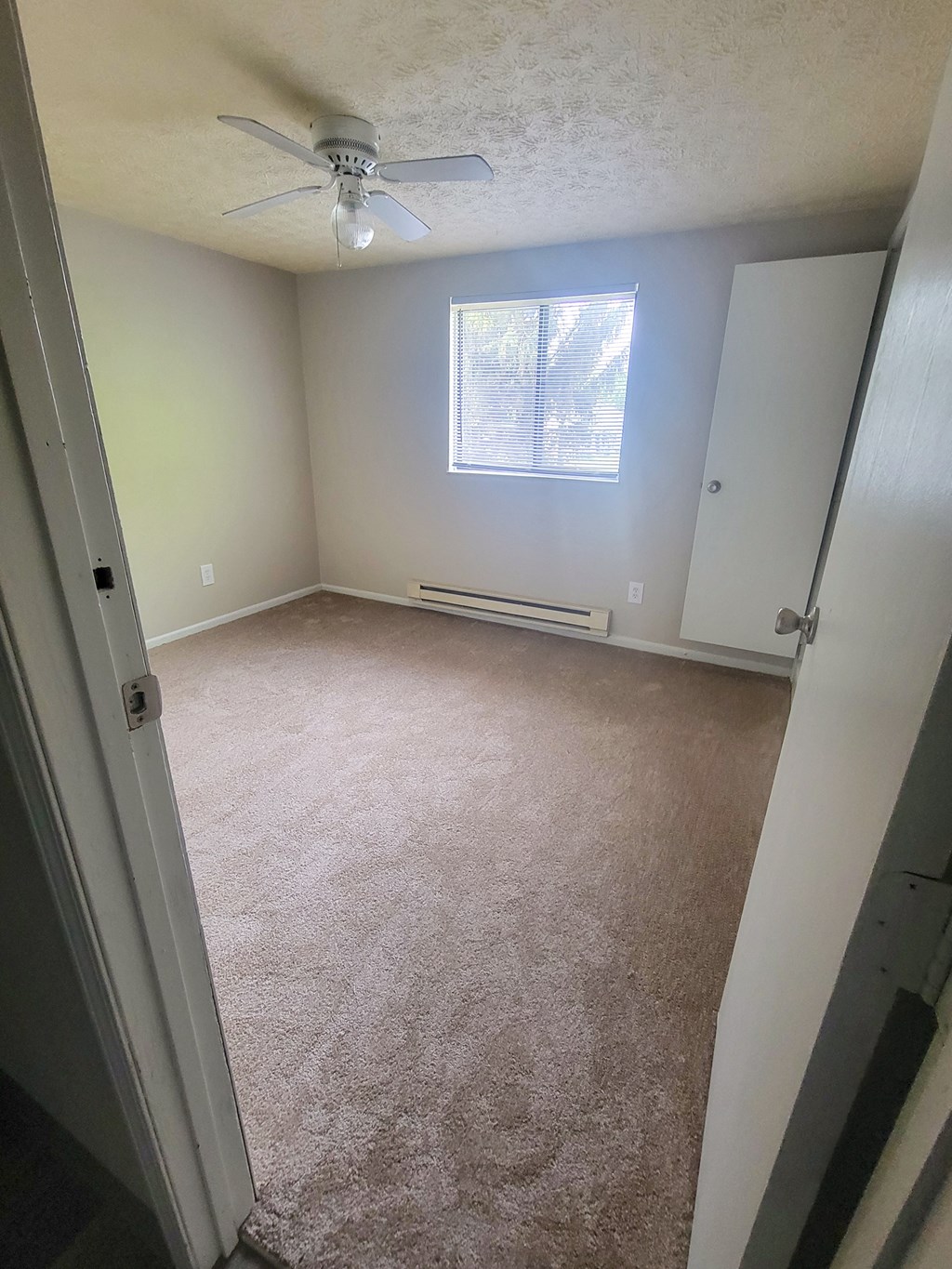 an empty room with a ceiling fan and a window