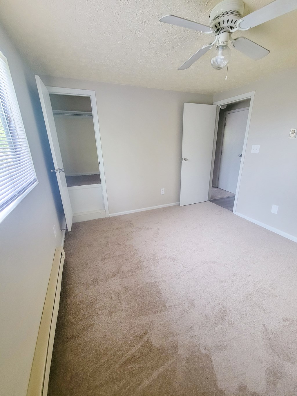 an empty bedroom with a ceiling fan