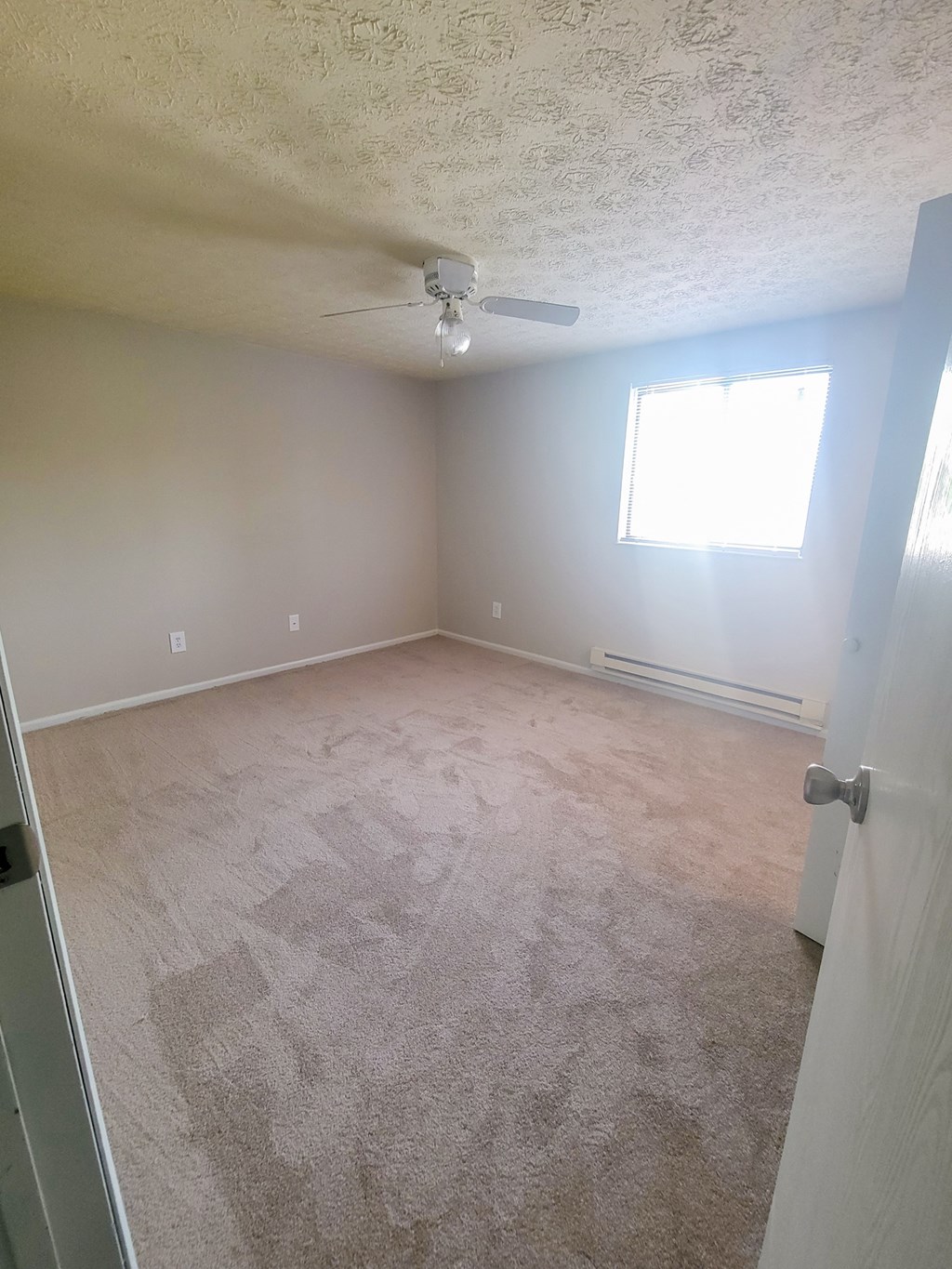 an empty room with a ceiling fan and a window