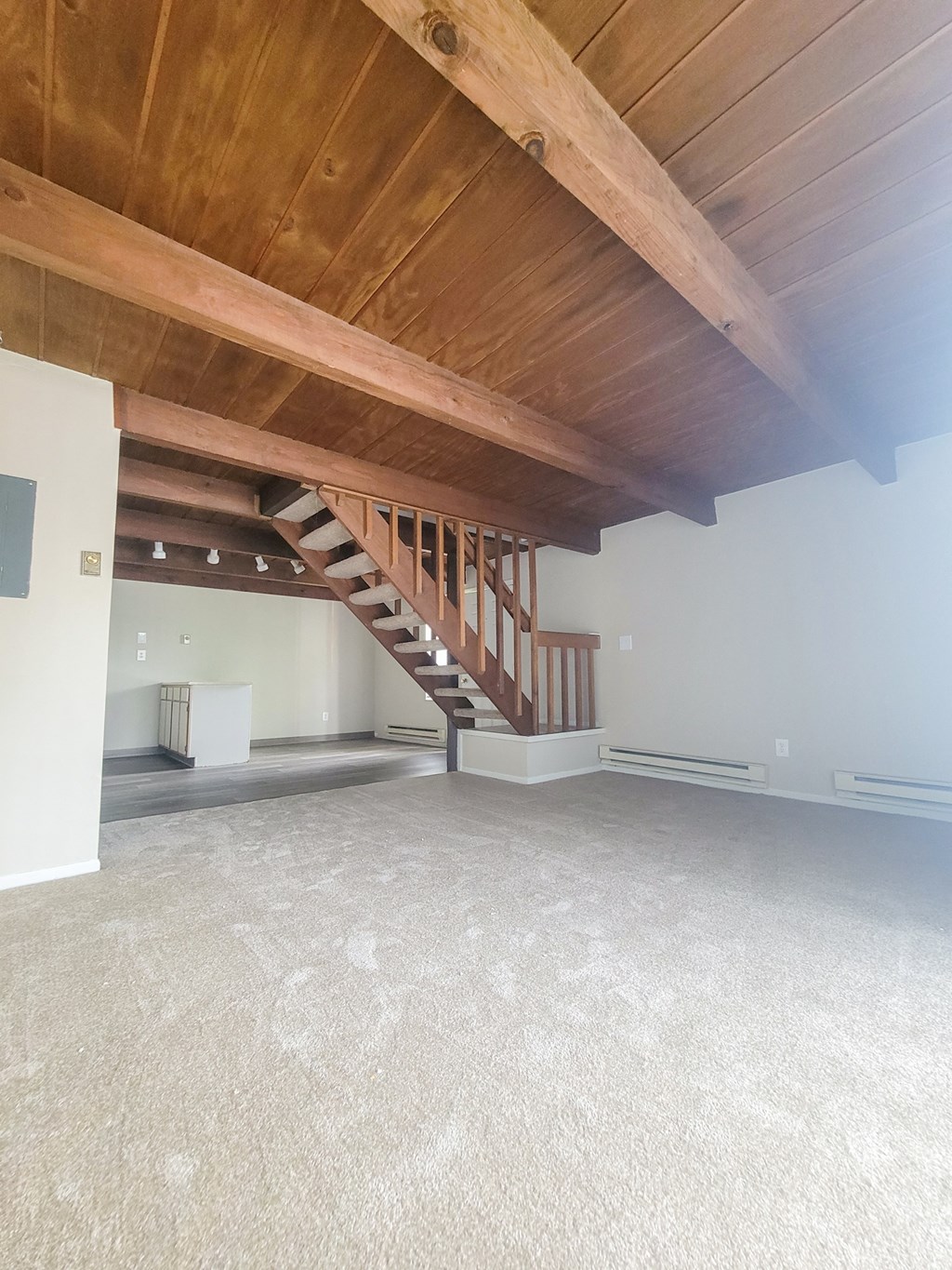 a large room with a wooden ceiling and stairs to the second floor