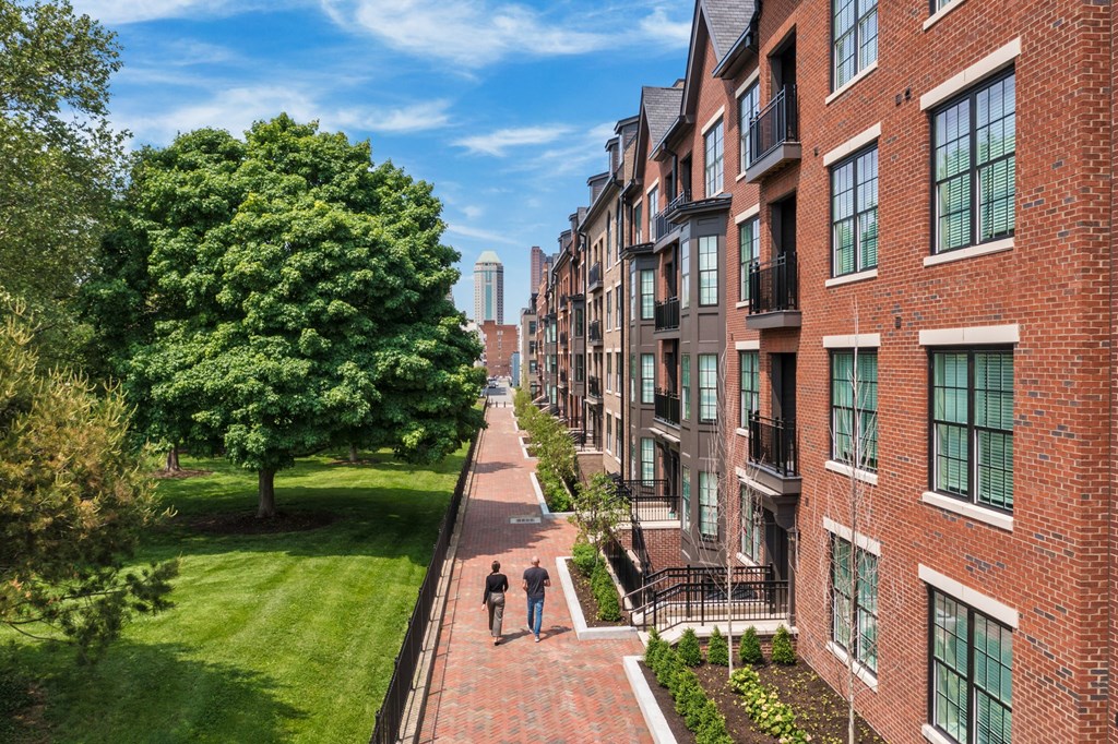 people walking down a sidewalk in front of apartments