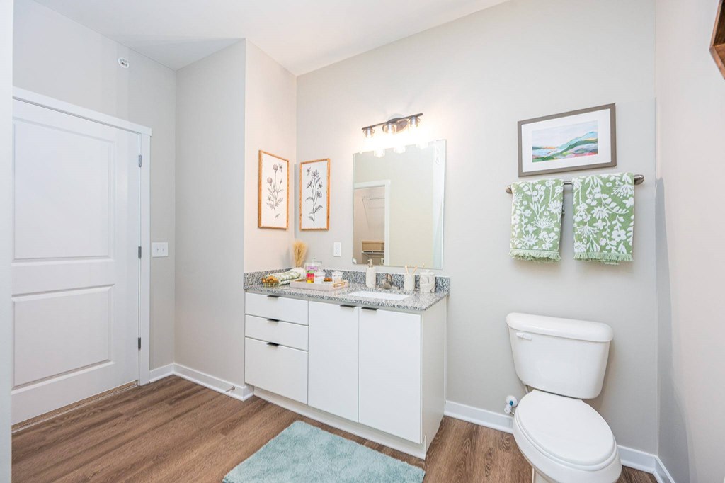 A white bathroom with a toilet, sink, and mirror.
