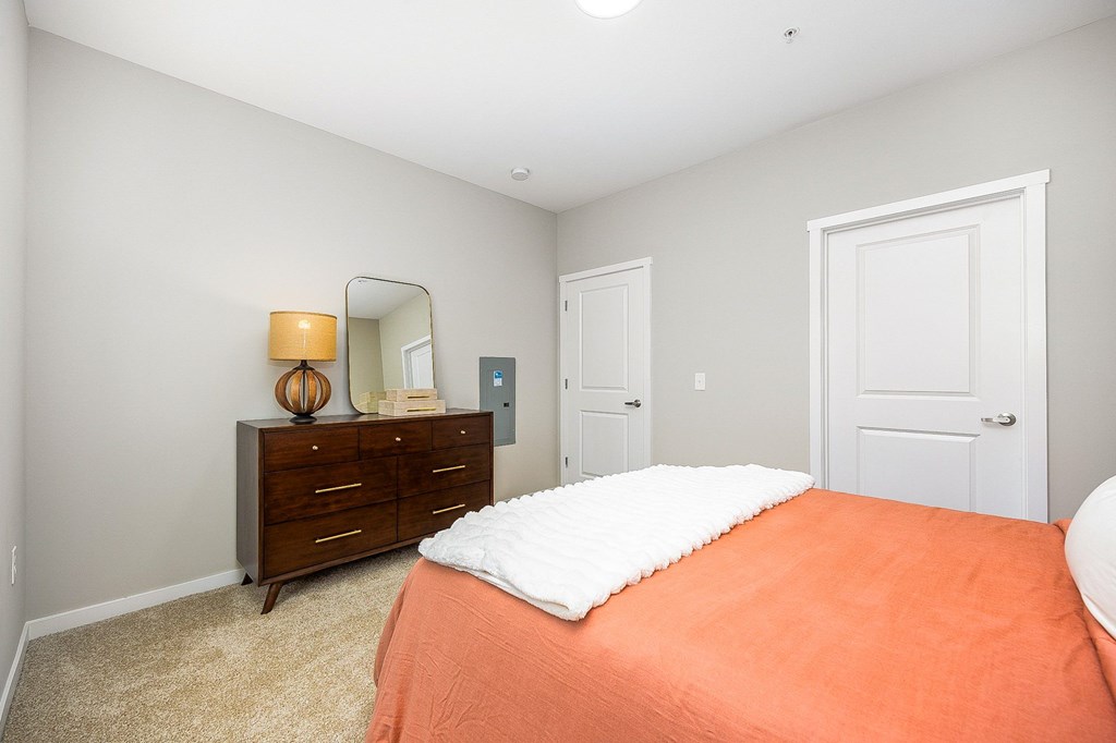 A bedroom with a bed, dresser, and mirror.