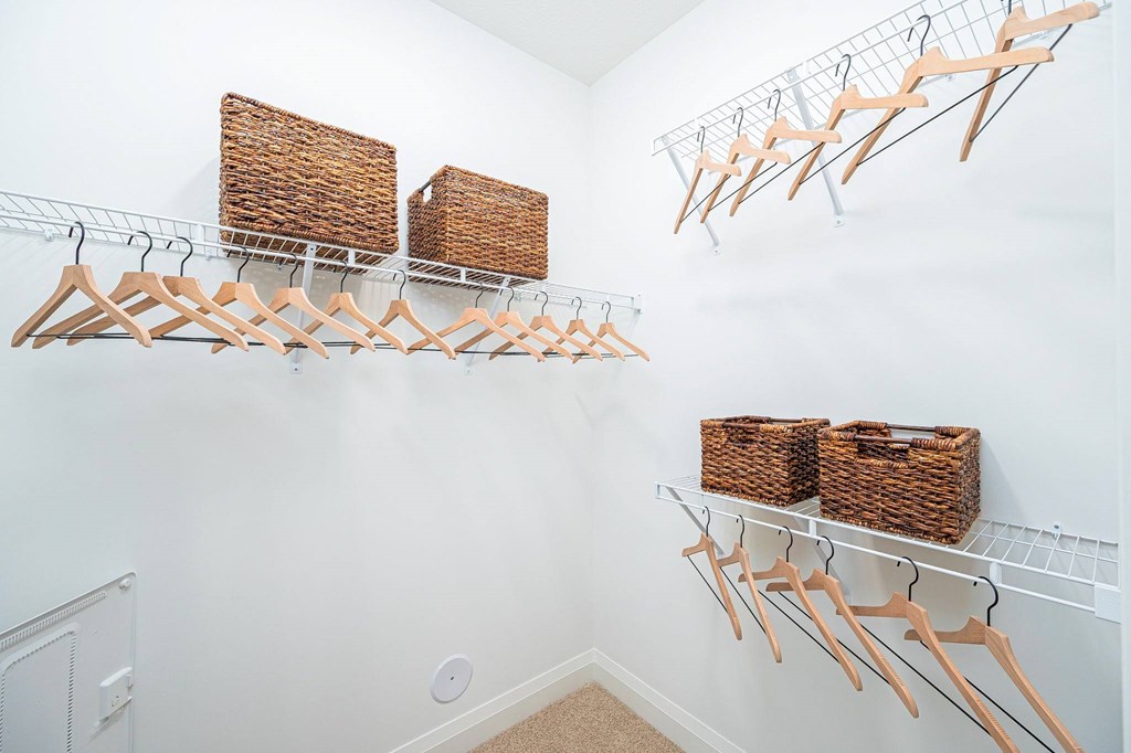 A white wall with clothes hangers and baskets.