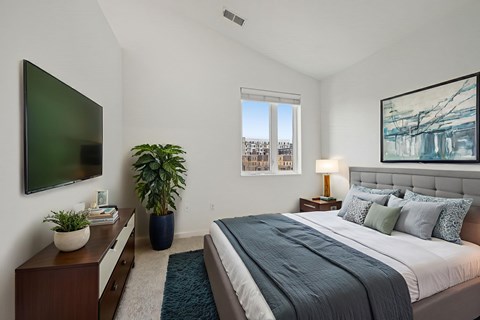 A bedroom with a large bed and a flat screen TV mounted on the wall.