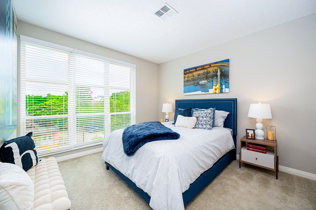 a bedroom with a blue and white bed and large windows