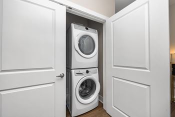 A white washing machine is in a white cabinet.