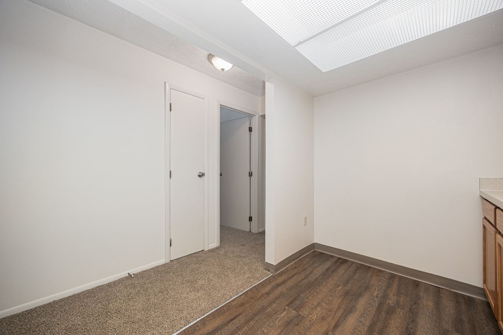 A room with a white door and a brown floor.