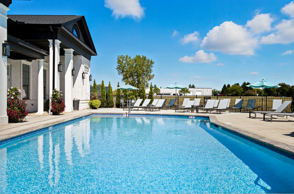 A swimming pool in front of a house with white columns.